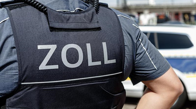 Ein Beamter trägt während seines Dienstes eine Schutzweste mit der Rückenaufschrift «Zoll». Foto: Markus Scholz/dpa/Symbolbild