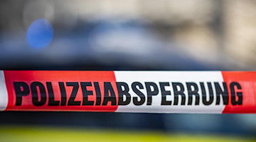 Ein Absperrband mit der Aufschrift «Polizeiabsperrung» ist vor einem Polizeiwagen aufgespannt. Foto: David Inderlied/dpa/Illustration