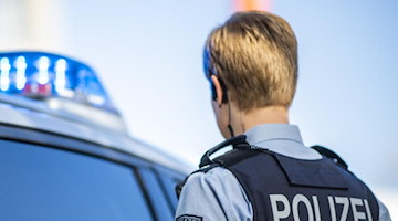 Eine Polizistin steht vor einem Streifenwagen. Foto: David Inderlied/dpa/Illustration