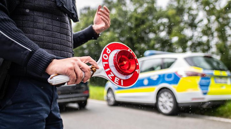 Eine Polizistin hält eine Winkerkelle in der Hand. Foto: Guido Kirchner/dpa/Symbolbild