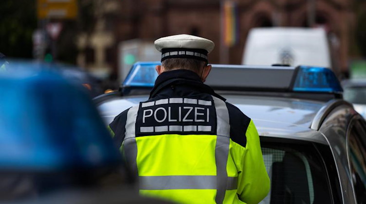 Ein Polizeibeamter steht zwischen zwei Einsatzfahrzeugen der Polizei. Foto: Philipp von Ditfurth/dpa/Symbolbild