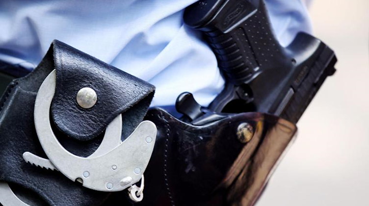 Ein Polizist mit Handschellen und Pistole am Gürtel. Foto: Oliver Berg/dpa