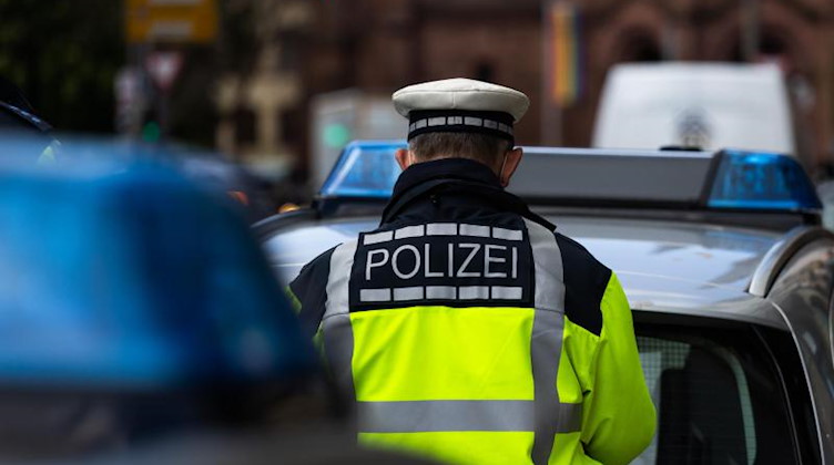 Ein Polizeibeamter steht zwischen zwei Einsatzfahrzeugen der Polizei. Foto: Philipp von Ditfurth/dpa/Symbolbild