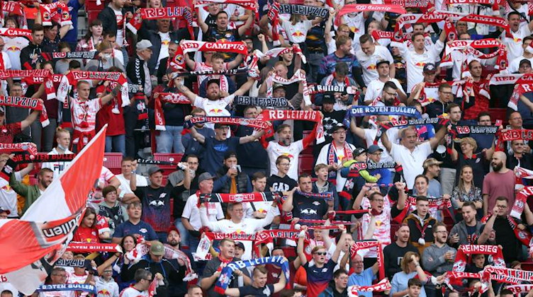 Fans von RB Leipzig zeigen ihre Schals und feuern die Mannschaft an. Foto: Jan Woitas/dpa/Archivbild