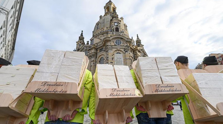Mitarbeiter einer Dresdner Bäckerei tragen Christstollen-Kisten einer speziellen Edition in die Frauenkirche. Foto: Robert Michael/dpa-Zentralbild/dpa