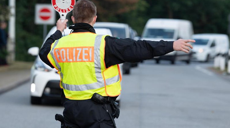 Ein Polizist mit einer Winkerkelle auf einem Autobahn-Parkplatz. Foto: Sebastian Kahnert/dpa-Zentralbild/dpa/Symbolbild