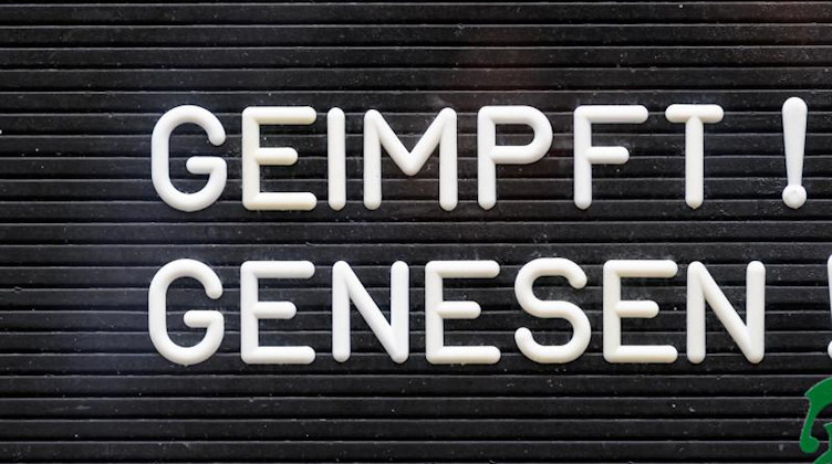 «Geimpft! Genesen!» steht auf einem Schild an einer Bar. Foto: Robert Michael/dpa-Zentralbild/dpa/Symbolbild