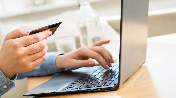 Eine Frau tippt ihre Kreditkarten-Daten in einen Laptop. Foto: Christin Klose/dpa-tmn/Symbolbild