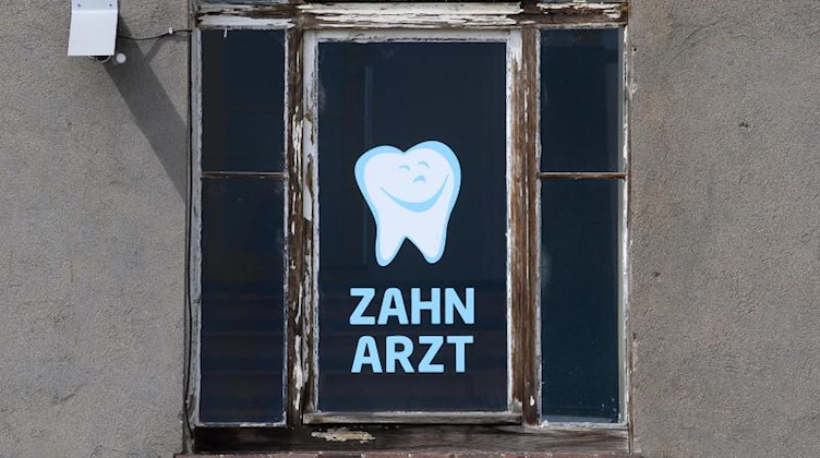 «Zahnarzt» steht in einem Fenster. Foto: Robert Michael/dpa/Symbolbild