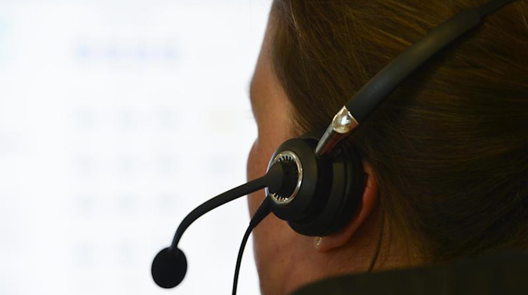 Eine Frau mit einem Headset sitzt an einem Arbeitsplatz. Foto: picture alliance / dpa/Symbolbild