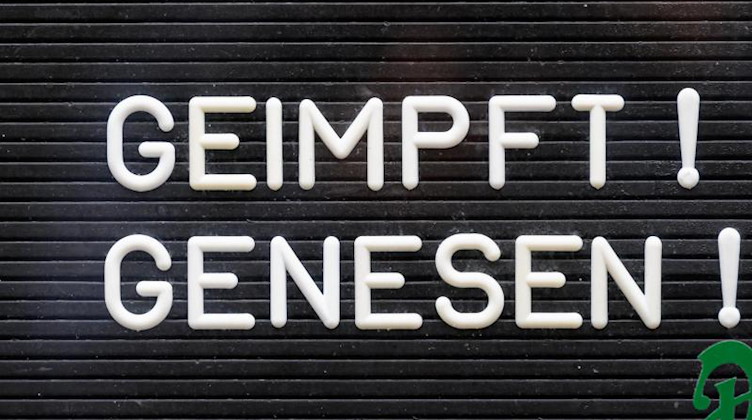 «Geimpft! Genesen!» steht auf einem Schild an einer Bar. Foto: Robert Michael/dpa-Zentralbild/dpa/Symbolbild