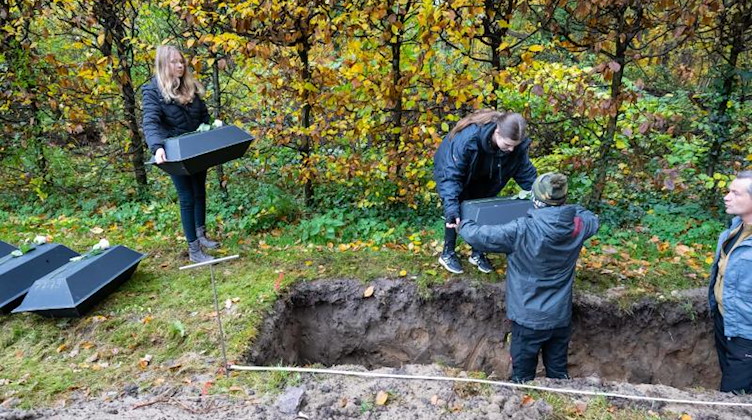 Schülerinnen und Schüler einer Dresdner Oberschule arbeiten mit bei der Einbettung von Kriegstoten. Foto: Matthias Rietschel/dpa
