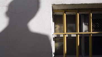 Der Schatten eines Mannes ist neben einem Gitterfenster zu sehen. Foto: Peter Endig/dpa-Zentralbild/dpa/Archiv