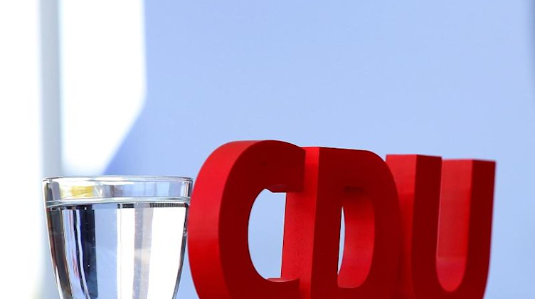 Ein CDU-Logo und ein Wasserglas stehen auf einem Tisch. Foto: Ronny Hartmann/dpa-Zentralbild/dpa/Archiv