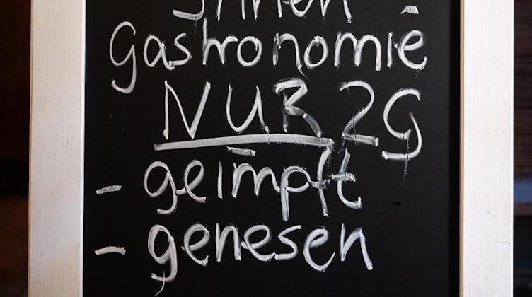 Eine Tafel mit dem Hinweis auf die 2G-Regelung steht in einem Gasthaus. Foto: Julian Stratenschulte/dpa