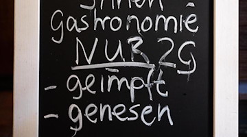 Eine Tafel mit dem Hinweis auf die 2G-Regelung steht in einem Gasthaus. Foto: Julian Stratenschulte/dpa