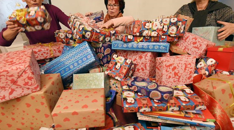 Frauen des Zonta-Clubs Leipzig packen über 200 Päckchen mit gesammelten Sachspenden für den Verkauf auf einem Weihnachtsmarkt. Foto: Waltraud Grubitzsch/dpa-Zentralbild/dpa