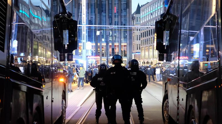 Polizisten stehen bei einer Kundgebung vgegen Corona-Maßnahmen auf dem Augustusplatz zwischen Wasserwerfern. Foto: Sebastian Willnow/dpa-Zentralbild/dpa