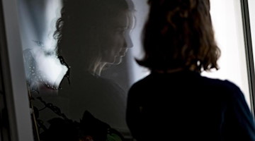 Eine junge Frau steht in einem geöffneten Fenster. Foto: Fabian Sommer/dpa/dpa-tmn/Symbolbild