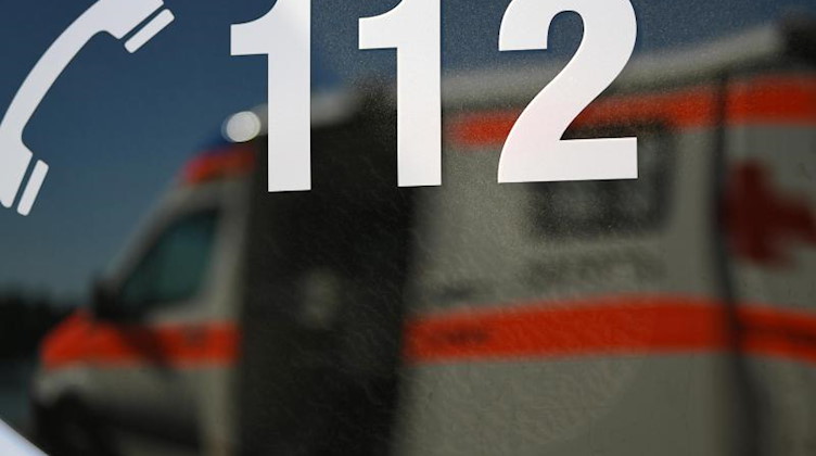 Ein Rettungswagen spiegelt sich in der Aufschrift "112". Foto: Patrick Seeger/dpa/Symbolbild