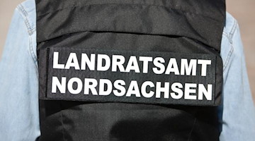 Ein Angestellter trägt eine Weste mit der Aufschrift «Landratsamt Nordsachsen». Foto: Oliver Killig/dpa-Zentralbild/dpa/Archivbild