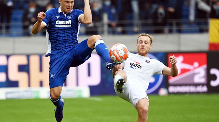 Der Karlsruher Marco Thiede und der Auer Ben Zolinski kämpfen um den Ball. Foto: Uli Deck/dpa/Bildarchiv