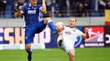 Der Karlsruher Marco Thiede und der Auer Ben Zolinski kämpfen um den Ball. Foto: Uli Deck/dpa/Bildarchiv