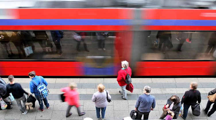 Zahlreiche Menschen warten an einer Haltestelle für Straßenbahnen. Foto: Jan Woitas/dpa-Zentralbild/dpa/Symbolbild