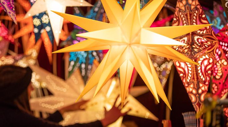 Bunte Weihnachtssterne werden an einem Stand auf dem Weihnachtsmarkt angeboten. Foto: Friso Gentsch/dpa/Symbolbild