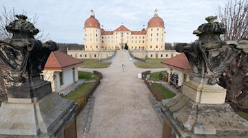 Passanten gehen vor dem Schloss Moritzburg entlang. Foto: Sebastian Kahnert/dpa-Zentralbild/dpa