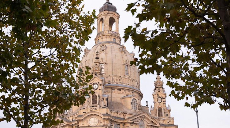 Herbstlich gefärbte Bäume rahmen die Kuppel der Frauenkirche auf dem Neumarkt. Foto: Sebastian Kahnert/dpa-Zentralbild/dpa