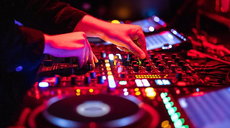 Ein DJ steht in einem Club am Mischpult. Foto: Matthias Balk/dpa/Symbolbild