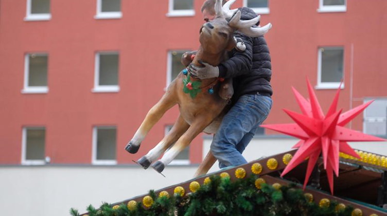 Ein Mann trägt eine Rentierfigur vom Dach eines Stands des Weihnachtsmarktes. Coronabedingt sind in Sachsen alle Weihnachtsmärkte abgesagt worden. Foto: Sebastian Willnow/dpa-Zentralbild/dpa/Bildarchiv
