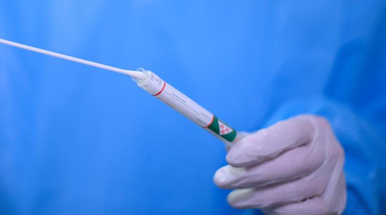 Ein Arzt hält einen Coronavirus-Test in den Händen. Foto: Robert Michael/dpa-Zentralbild/dpa/Symbolbild