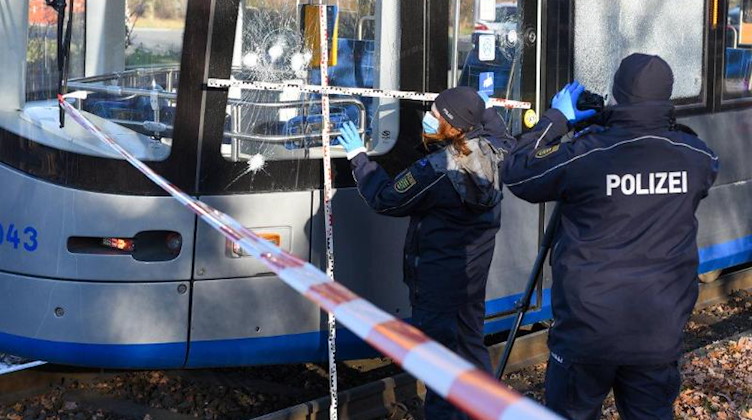 Polizisten begutachten eine zersplitterte Scheibe einer Straßenbahn. Foto: Erik-Holm Langhof/Lausitznews.de/dpa