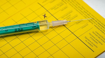 Eine Spritze liegt auf einem Impfpass. Foto: Friso Gentsch/dpa/Illustration