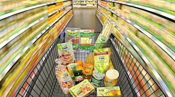 Ein Einkaufswagen mit Lebensmitteln wird durch einen Supermarkt geschoben. Foto: Julian Stratenschulte/dpa