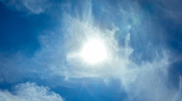 Die Sonne scheint durch leichte Zirrus-Wolken hindurch. Foto: Markus Scholz/dpa/Symbolbild