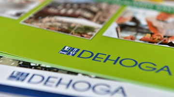 Zwei Prospekte mit dem Logo der Dehoga liegen während einer Pressekonferenz auf einem Tisch. / Foto: Marc Tirl/dpa-Zentralbild/dpa/Archivbild