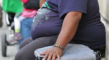Eine übergewichtige Person sitzt auf einer Bank. / Foto: Frank Leonhardt/dpa/Archivbild