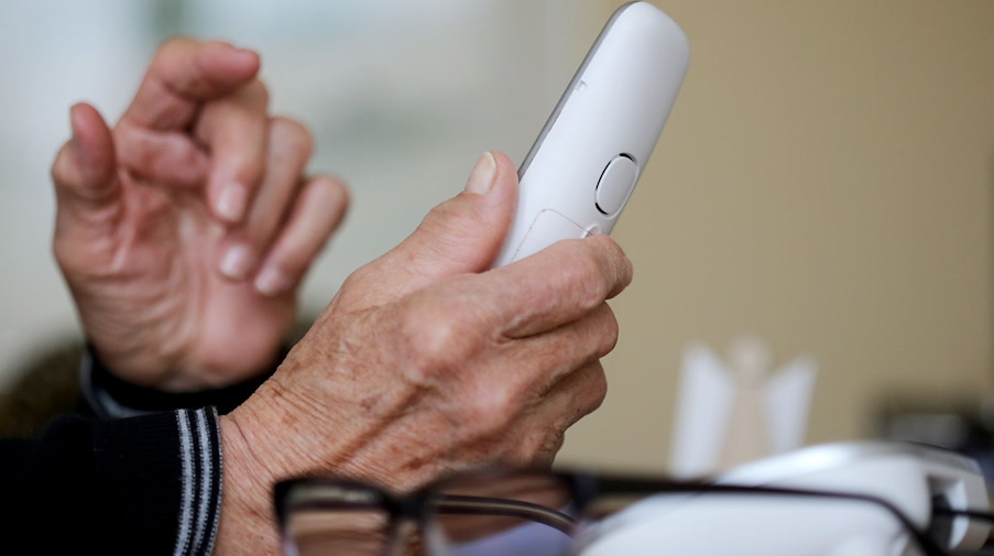 Eine ältere Person nimmt in ihrer Wohnung ein Telefongespräch an. / Foto: Roland Weihrauch/dpa/Symbolbild