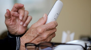 Eine ältere Person nimmt in ihrer Wohnung ein Telefongespräch an. / Foto: Roland Weihrauch/dpa/Symbolbild