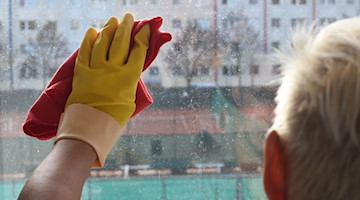 Eine Reinigungskraft putzt ein Fenster in einer Wohnung. / Foto: Jens Kalaene/dpa-Zentralbild/dpa/Symbolbild