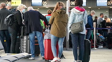 Reisende warten mit Gepäck am Check-in am Flughafen Leipzig/Halle. / Foto: Peter Endig/dpa-Zentralbild/dpa/Archivbild