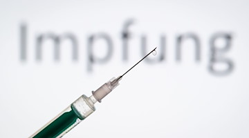 Eine Spritze wird vor den Schriftzug «Impfung» gehalten. / Foto: Friso Gentsch/dpa/Symbolbild