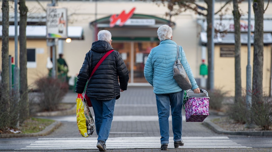 Zwei Frauen laufen mit Taschen und Korb auf dem Parkplatz eines Einkaufszentrums in Freital. / Foto: Daniel Schäfer/dpa-Zentralbild/dpa/Archivbild