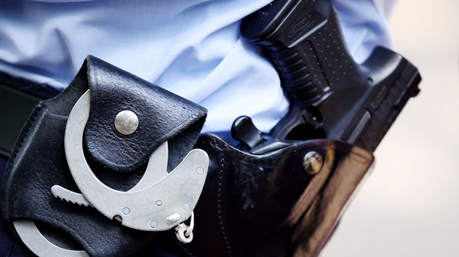 Ein Polizist mit Handschellen und Pistole am Gürtel. / Foto: Oliver Berg/dpa/Symbolbild
