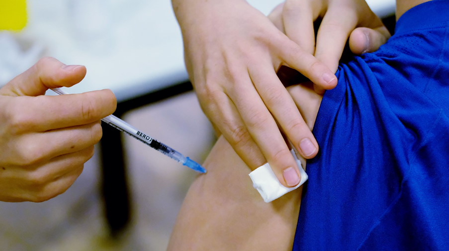 Ein Mitarbeiter eines Impfzentrums impft einen Jugendlichen gegen Corona. / Foto: Sebastian Willnow/dpa-Zentralbild/dpa/Symbolbild