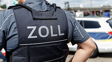 Ein Beamter trägt eine Schutzweste mit der Aufschrift «Zoll». / Foto: Markus Scholz/dpa/Symbolbild