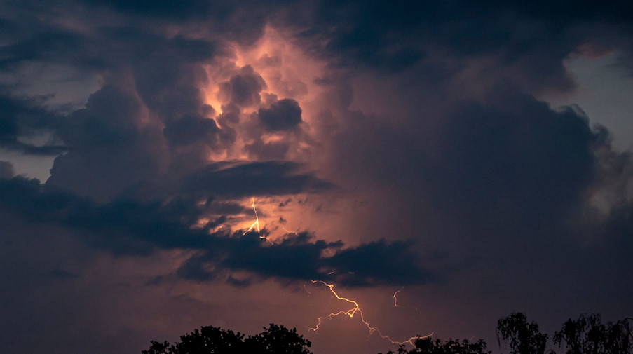 Ein Blitz hellt hinter dunklen Wolken auf. / Foto: Fabian Sommer/dpa/Symbolbild